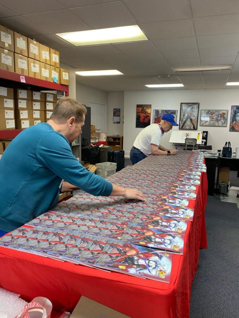Gatecrasher artist Billy Tucci and writer J.C. Vaughn signing hundreds of books for shipping.